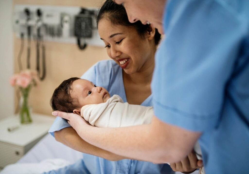 A baby being handed to a woman