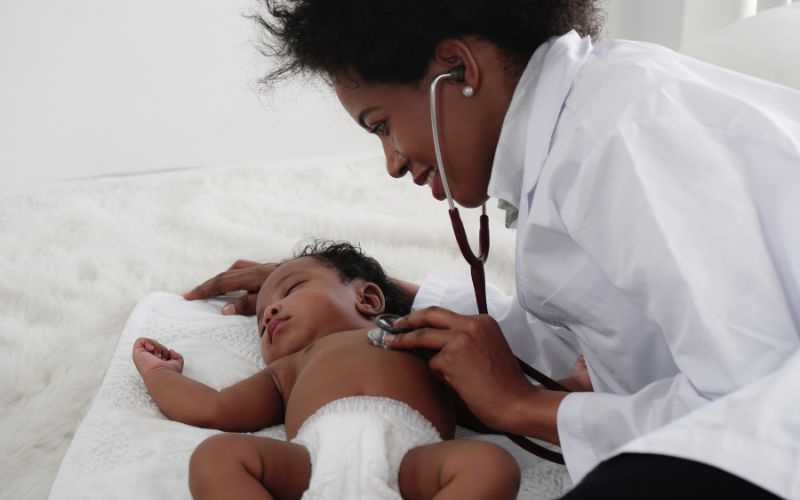 pediatrician holding a stethoscope over a baby