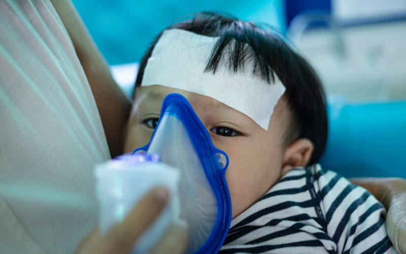 mother helping little son using nebulizer