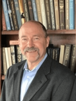 Man smiling in front of bookshelf.
