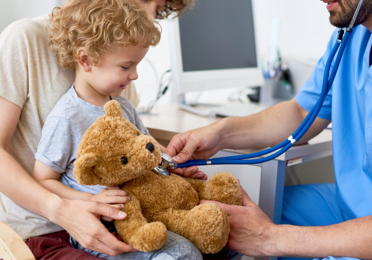 A young boy with his teddy bear being checked